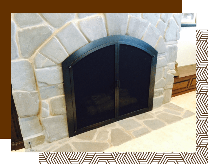 A fireplace with a black door and stone surround.